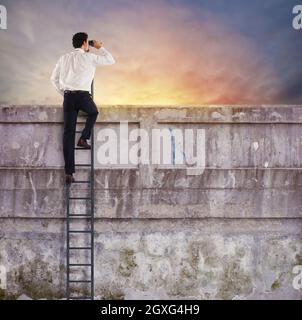 Uomo d'affari su una scala guarda lontano per nuove imprese Foto Stock