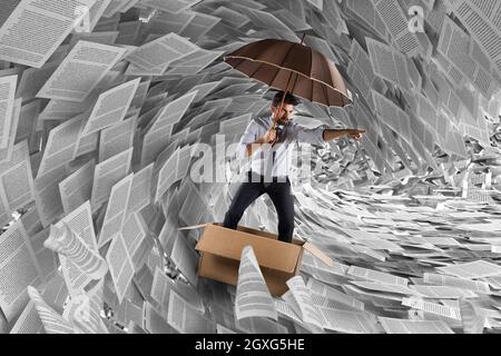 Concetto della tempesta di burocrazia con un uomo che naviga in un cartone nel mare di fogli Foto Stock