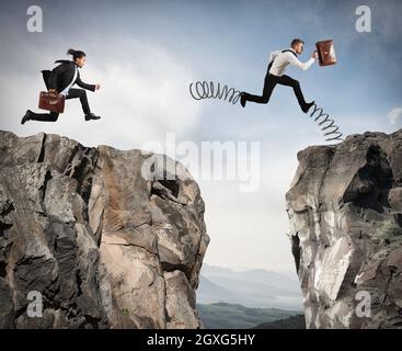 Uomo d'affari con la primavera corre contro un altro uomo d'affari tra due montagne Foto Stock