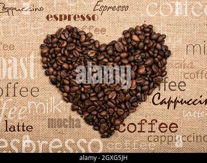 Sfondo di chicchi di caffè a forma di cuore su sfondo burlap Foto Stock