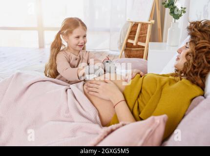 La mamma incinta gioca con sua figlia. Concetto di famiglia Foto Stock