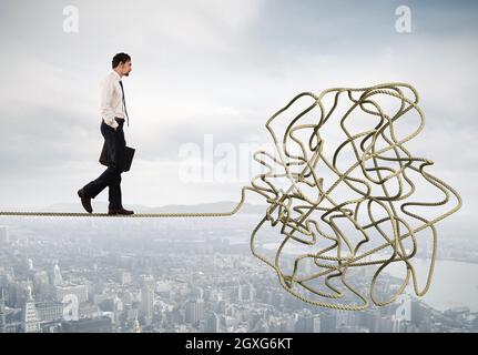 Problem and difficulty concept with a businessman who walk on a tangled rope Stock Photo