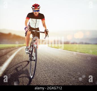 Vista frontale di un ciclista stradale in uniforme durante una gara al tramonto Foto Stock