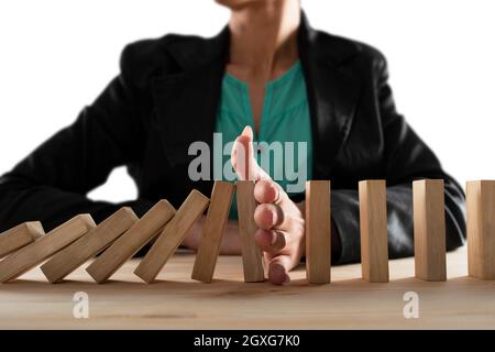 Imprenditrice si arresta una catena cadere come gioco di domino giocattolo. Concetto di prevenire le crisi e fallimento in business Foto Stock