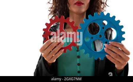 Imprenditrice tenta di collegare pezzi di ingranaggi. Concetto di lavoro di squadra, di partenariato e di business integration Foto Stock