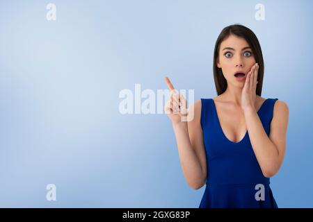 Sorpresa bella ragazza indica uno spazio vuoto per il tuo testo Foto Stock