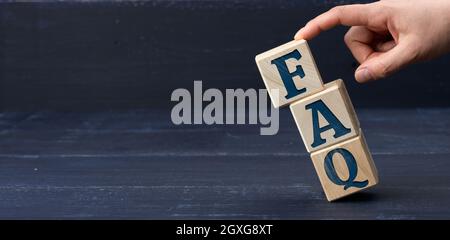 Iscrizione FAQ (domande frequenti) su blocchi di legno su sfondo blu. Concetto di QA, guida e suggerimenti, maniglie che cadono cubi Foto Stock