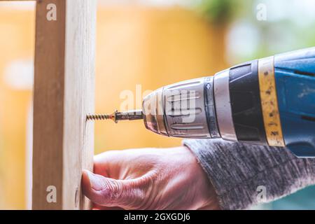 Fai da te l'handyman a casa sta usando un cacciavite cordless per l'avvitamento Foto Stock