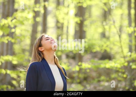 Una donna informale e rilassata respira aria fresca in una foresta verde Foto Stock