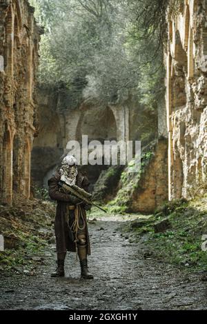 Post-apocalisse nucleare. Unico sopravvissuto in tatters e maschera a gas sulle rovine della città distrutta Foto Stock