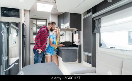 Donna e uomo che testano l'interno di camper vogliono comprare o affittare controllando l'angolo cottura Foto Stock