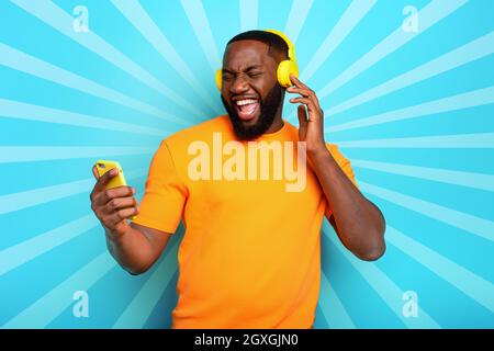 Ragazzo con auricolare giallo ascolta musica e danze. emozionale e espressione energica Foto Stock