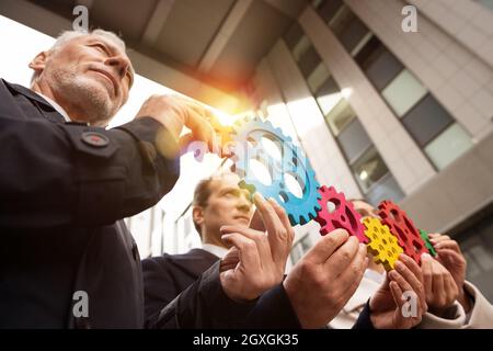 Il lavoro di squadra di operatori lavorano insieme e unire pezzi di ingranaggi. Accordo di partenariato e di concetto di integrazione Foto Stock