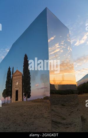 Antica chiesa di Vitaleta riflessa nel monumento di Abbbraccio di luce di Helidon Xhixha al tramonto a San Quirico d'Orcia, nei pressi di Pienza, Toscana, i