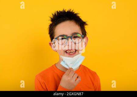 Il bambino è felice di rimuovere la maschera per il coronavirus covid-19 Foto Stock