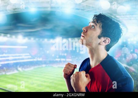 Appassionato di calcio alla stadio illuminato con gesto di vittoria Foto Stock