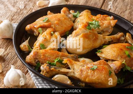 Pollo di cucina spagnola fritto con aglio, timo e rosmarino primo piano in un piatto sul tavolo. Orizzontale Foto Stock