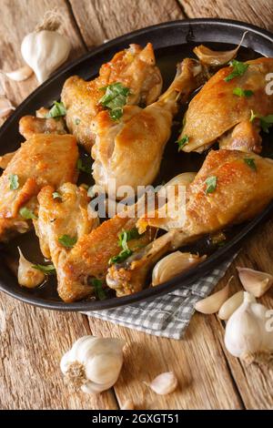 Pollo all'aglio spagnolo Pollo al Ajillo primo piano su un piatto sul tavolo. Verticale Foto Stock