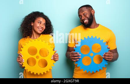 Coppia con ingranaggi su sfondo azzurro. Concetto di integrazione, Unione, rapporto e partenariato Foto Stock