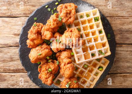 Pezzetti di pollo impanato e cialde croccanti con salsa al miele da vicino su un piatto di ardesia sul tavolo. Vista dall'alto orizzontale Foto Stock