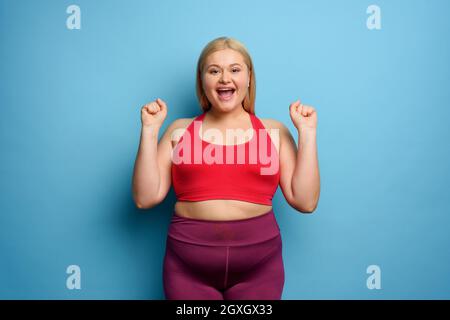 Fat ragazza fa palestra a casa. Soddisfatto e espressione con successo. Foto Stock