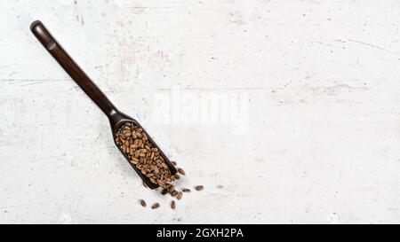 Beato latte di cardo semi - Silybum marianum - in piccolo cucchiaio di legno su pietra bianca come asse, vista dall'alto, spazio per testo lato destro. Foto Stock