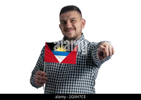 Ragazzo bianco che tiene una bandiera di Antigua e Barbuda e punta in avanti di fronte a lui isolato su uno sfondo bianco. Foto Stock