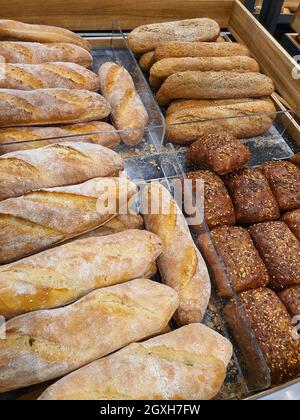 Varietà di diversi tipi di pane, baguette e panini hot dog in un panificio o negozio di alimentari. Primo piano appena sfornato Foto Stock