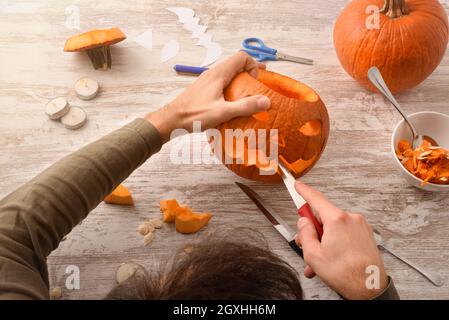 Dettaglio di uomo che intagliano e svuotano una zucca per la festa di Halloween. Vista dall'alto. Composizione orizzontale. Foto Stock