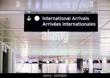 Cartello per gli arrivi internazionali in inglese e francese presso la sala del terminal dell'aeroporto. Confine aperto governativo per i visitatori internazionali. Foto Stock