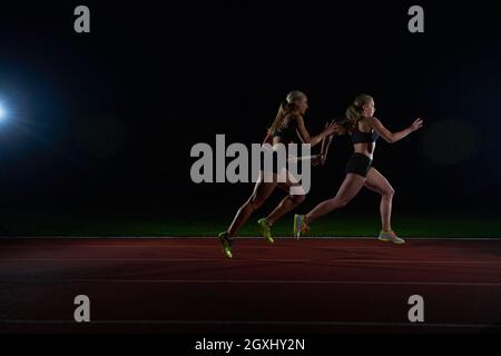 Donna corridori atletici passando il testimone nella staffetta Foto Stock