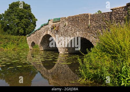 Stone Bridge attraverso il lago Serpentine presso la Waverley Abbey House, vicino a Farnham, Surrey, Inghilterra, Regno Unito. Foto Stock