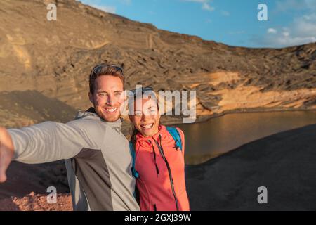 Viaggio estate Spagna destinazione selfie di coppia interrazziale turisti selfie foto su escursione donna asiatica, uomo caucasico escursionisti felice. Lanzarote National Foto Stock