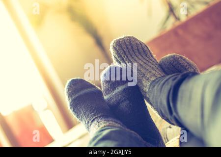 Piedi con i calzini di lana in inverno: matura è rilassante sul lettino Foto Stock