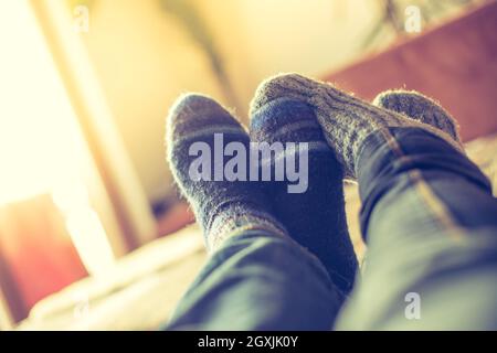 Piedi con i calzini di lana in inverno: matura è rilassante sul lettino Foto Stock