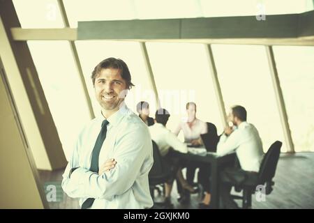 Business handosme manportrait al moderno luminoso ufficio in ambienti interni con il suo team nel gruppo lavorano insieme in background Foto Stock