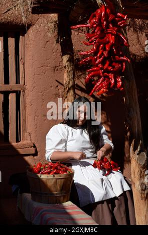 Una donna dimostra come fare le stras, o corde di peperoncini del cile, al complesso di storia vivente El Rancho de Las Golondrinas nel nuovo Messico. Foto Stock