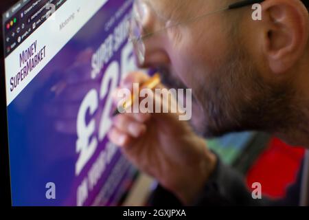 Uomo che guarda il sito internet di Money supermarket Moneysupermarket Foto Stock