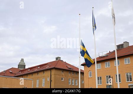 La bandiera svedese a mezza pole, presso la stazione di polizia di Linköping, dopo la morte di due poliziotti a Skåne in relazione ad una missione di protezione e al trasporto dell'artista Lars Vilks, anch'esso morto nell'incidente stradale che si è verificato in quel paese. Foto Stock