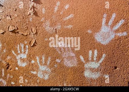 Giochi per bambini con gesso, colore della polvere dalle palme, come le stampe a mano sulla parete ruvida facciata sfondo, infanzia design. Foto Stock