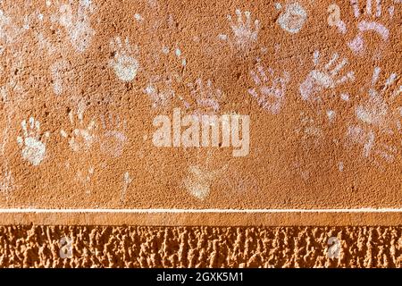 Giochi per bambini con gesso, colore della polvere dalle palme, come le stampe a mano sulla parete ruvida facciata sfondo, infanzia design. Foto Stock