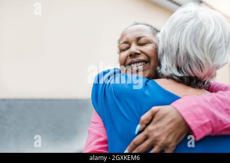 Donne anziane multirazziali che si abbraccia - amicizia anziana e concetto di amore - Focus sul volto della donna africana Foto Stock