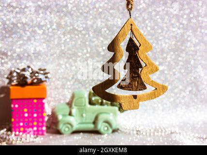 Albero di Natale in legno e giocattolo stellare su sfondo di neve bokeh chiaro e scintillante in argento. Concetto festivo. Felice arredamento di Capodanno. Souveni fatti a mano Foto Stock