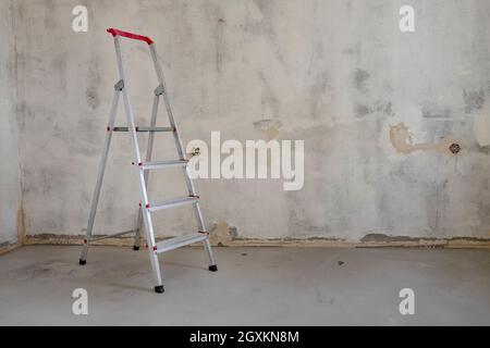 La scala a cavalletto si trova in una stanza vuota Foto Stock