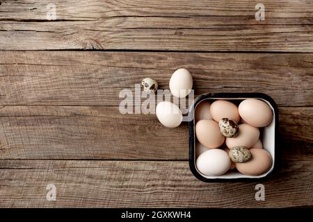 Pollo biologico e uova di quaglia in scatola di metallo su sfondo di legno. Concetto domestico biologico con uova da galline allevate di free-range e pascolo Foto Stock