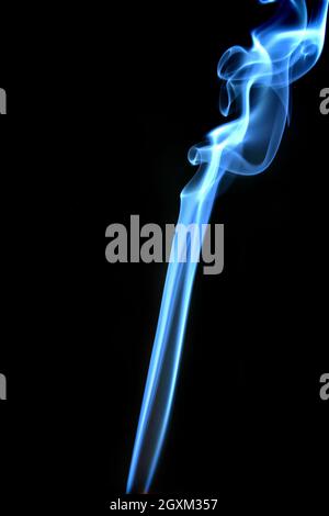 Fumo blu che si alza in forma astratta su sfondo nero Foto Stock