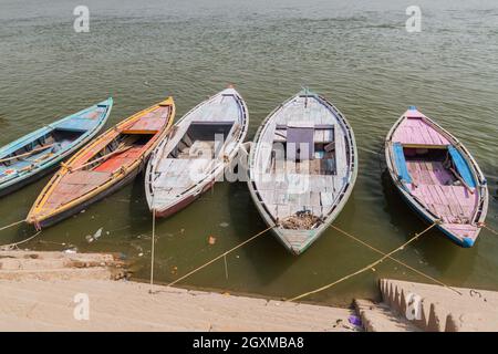 Piccole barche vicino Ghats lungofiume gradini che portano alle rive del fiume Ganges in Varanasi, India Foto Stock