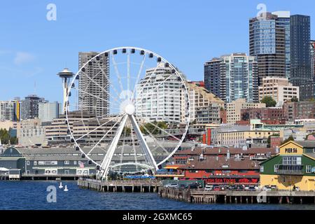 Vista sul lungomare del centro di Seattle con la ruota panoramica Seattle Great Ride al molo 57, lo Space Needle, il molo 56 e l'acquario di Seattle al molo 59. Foto Stock