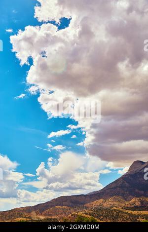 Nuvole incombenti sulle montagne del deserto contro il cielo blu Foto Stock