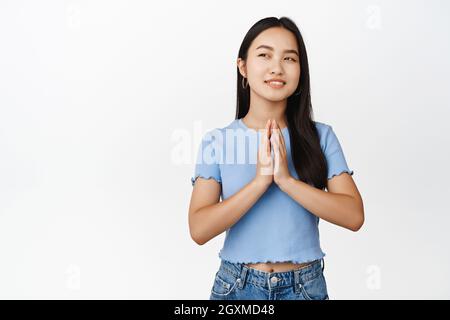 La donna asiatica premurosa ha un piano, le dita del campanile e sorridente con il viso smug, guardando in su felice, idea interessante, schemando su sfondo bianco Foto Stock